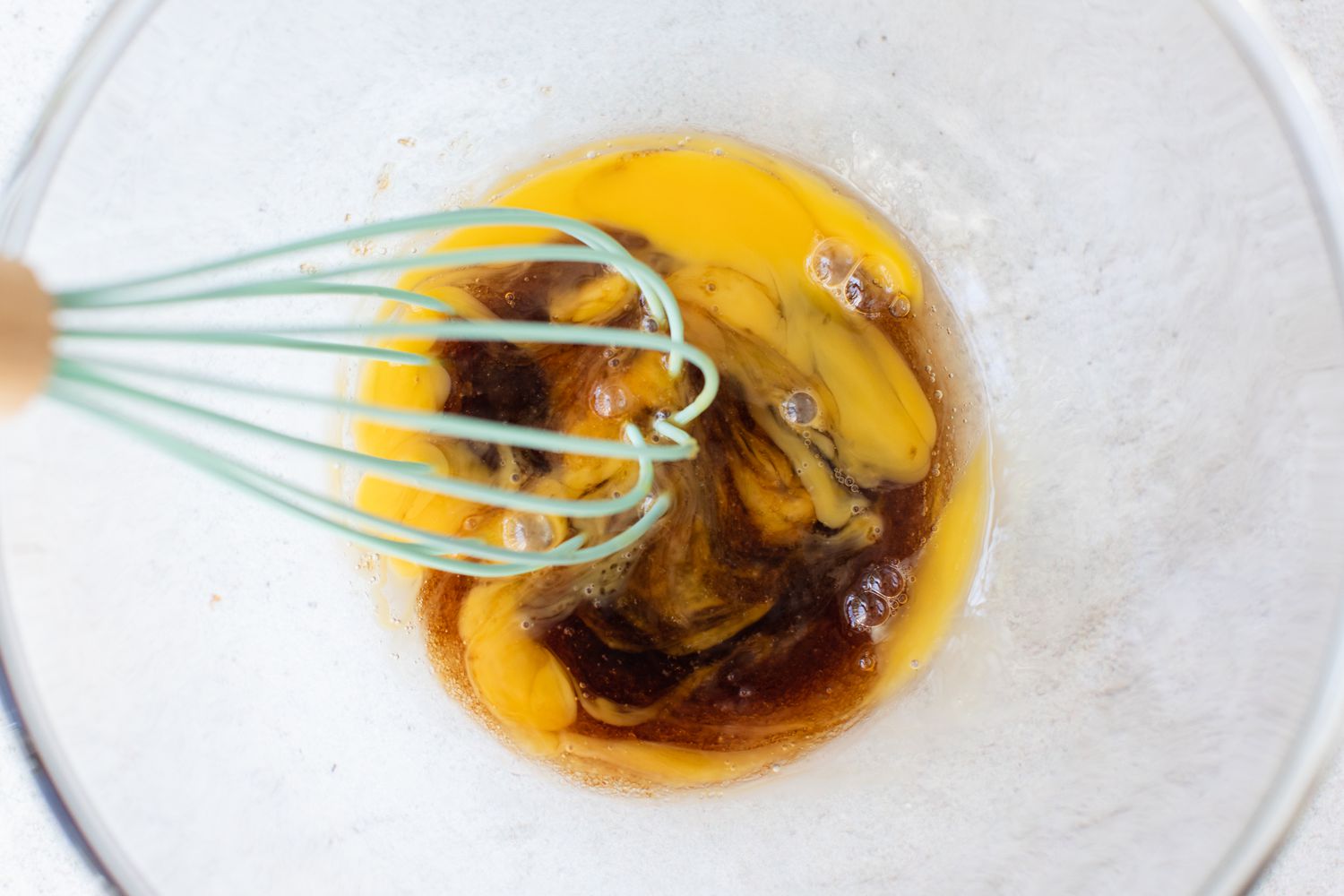 Mixing brown sugar and an egg in a bowl to make Rice Pudding