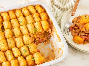 cowboy casserole in a casserole dish next to a plate with a serving