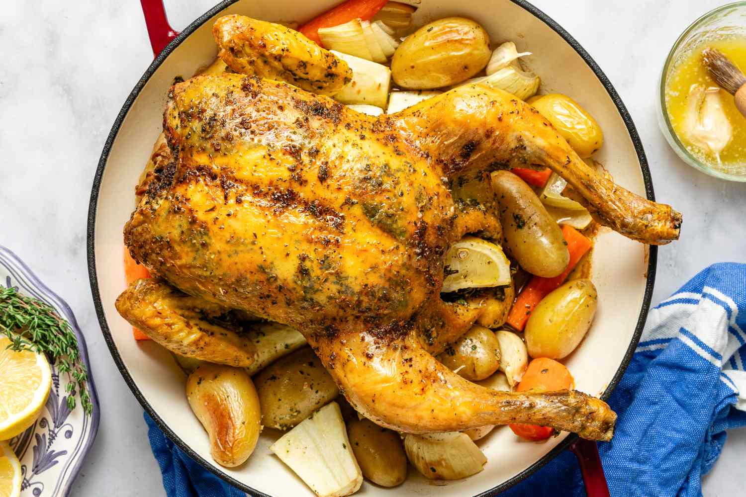 Cooked roast chicken in a dish with potatoes and vegetables