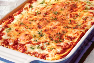 Lasagna in a casserole dish and topped with dried basil
