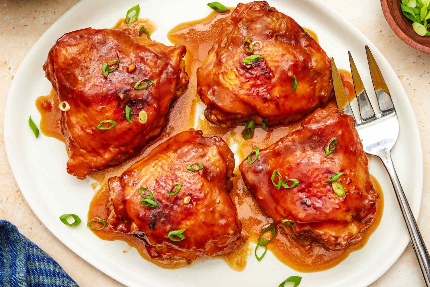 Overhead view of shoyu chicken on a white serving platter with a large serving fork