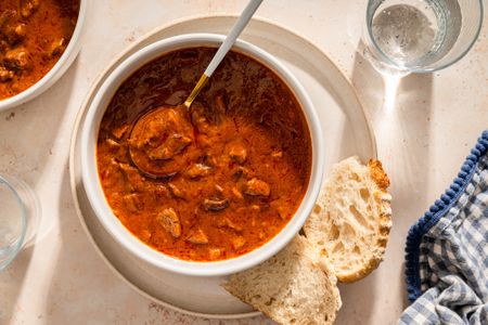overhead view of a bowl of Grandma Helen’s Beefy Tomato Soup with a side of bread