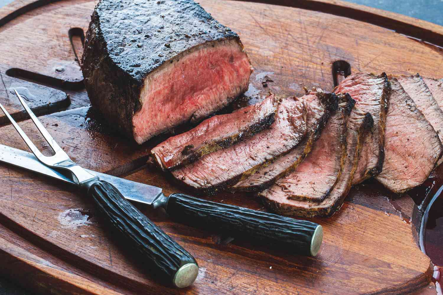 London broil being sliced on a cutting board.