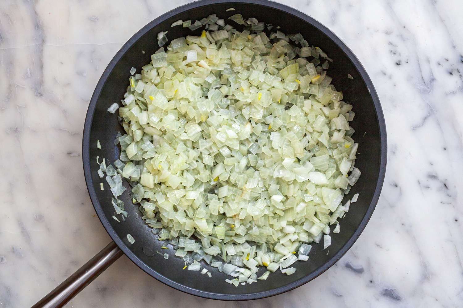 Making an onion jam recipe with balsamic vinegar by sauteeing onions in a skillet.