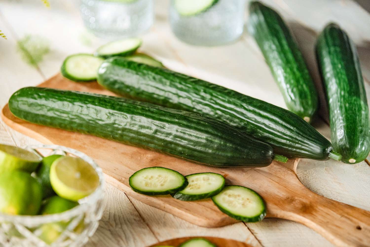 Four large green cucumbers top view composition on a wood chopping table and some slices