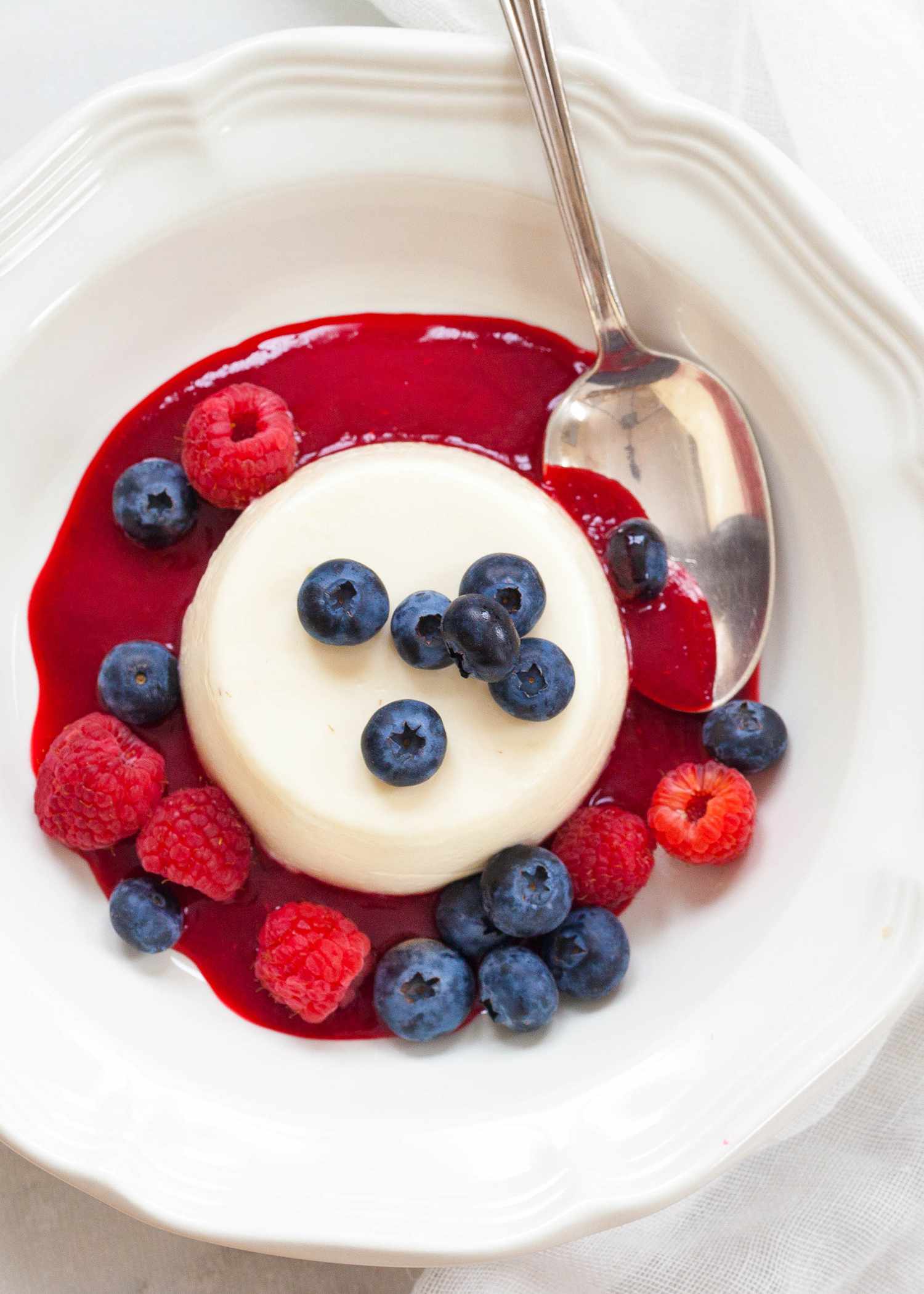 Panna cotta in a round bowl topped with blueberries and raspberries
