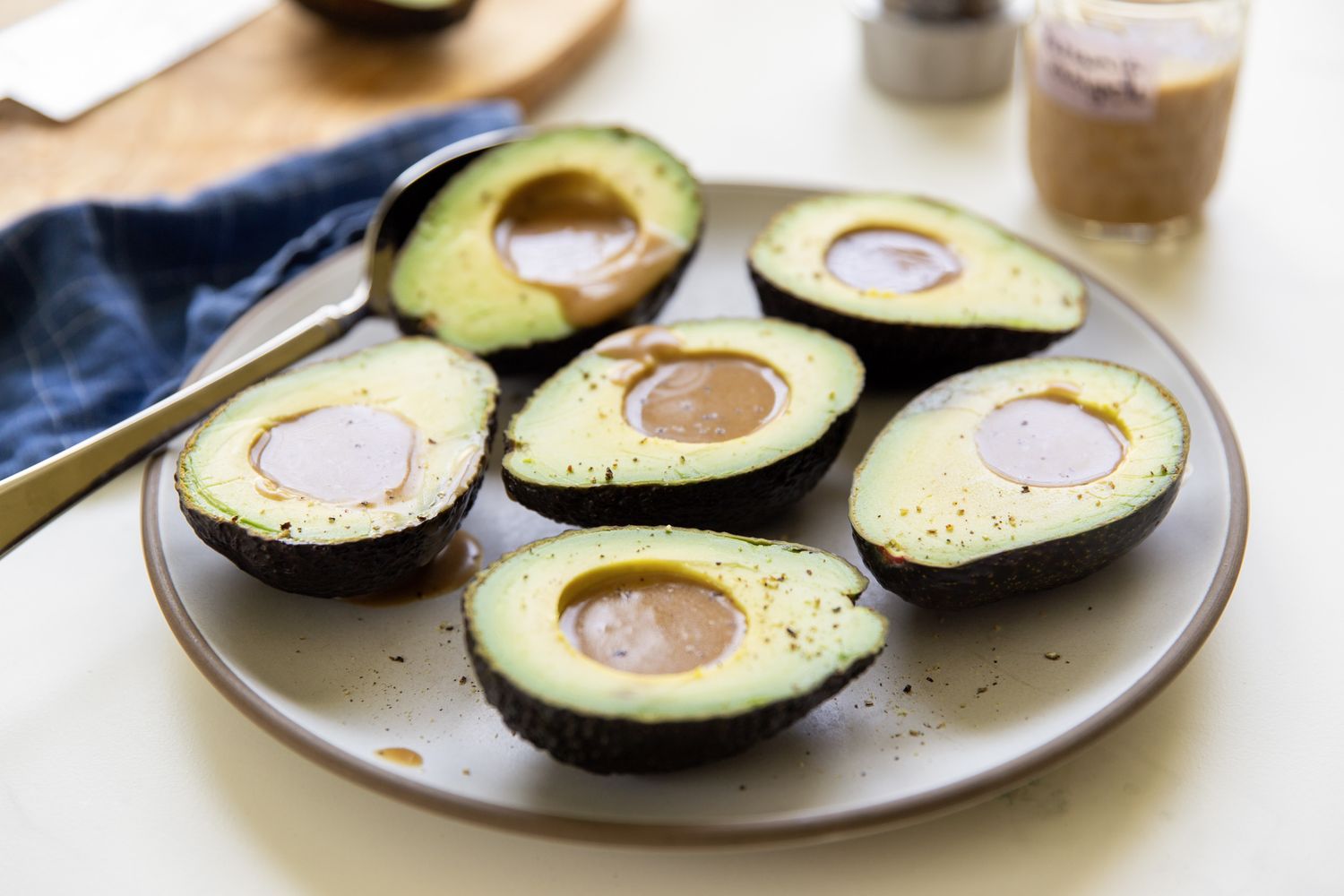 Halved avocados with dressing placed on a plate presented as part of a simple salad preparation