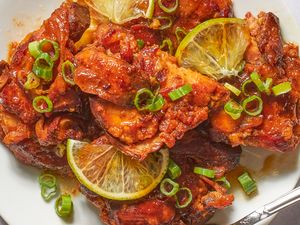 Plate of glazed chicken pieces garnished with lemon slices and green onions