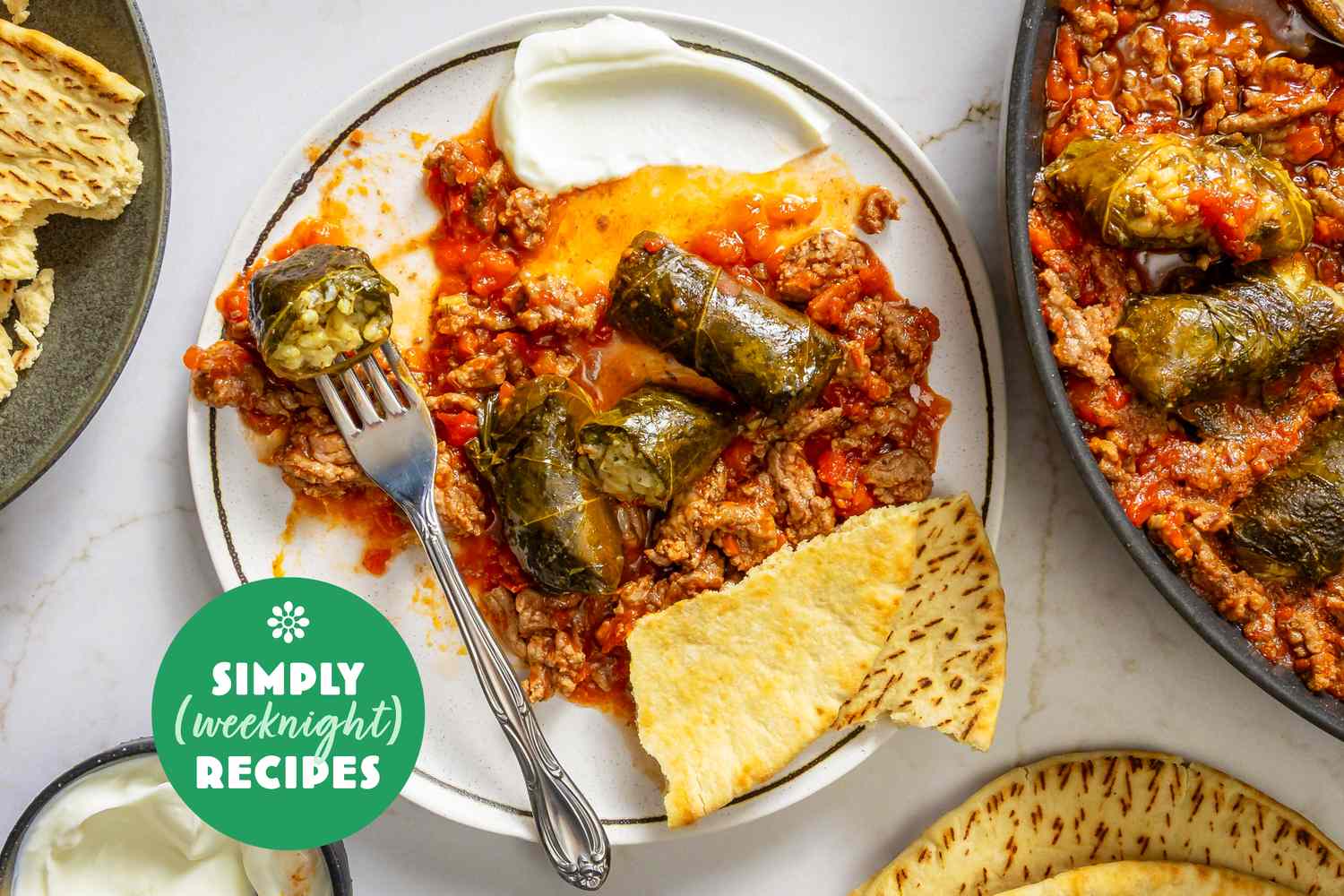 A plate of stuffed grape leaves with a side of flatbread and yogurt dip part of a Simply Weeknight Recipes presentation