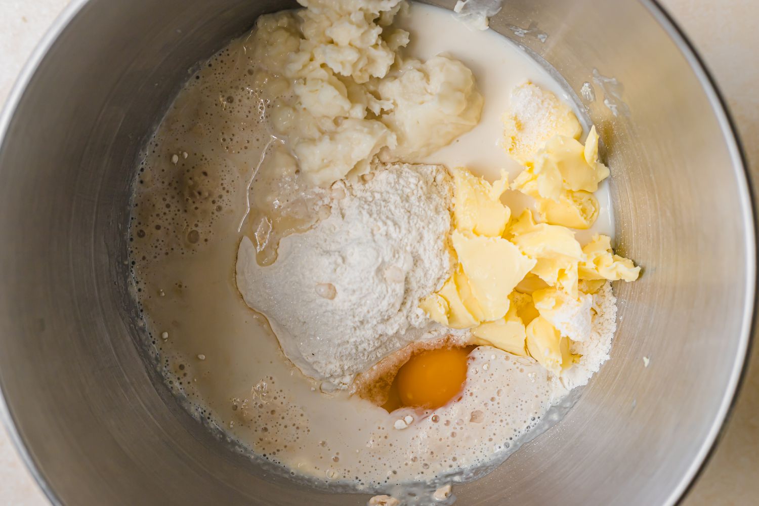 Adding ingredients for pull apart rolls with garlic and parmesan into a mixing bowl.