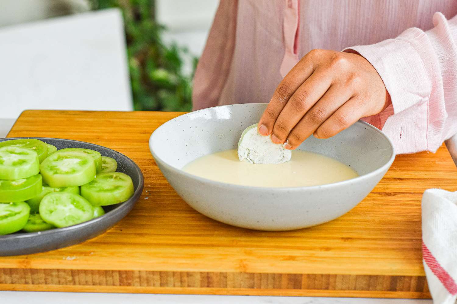 Dipping floured green tomato in egg mixture.