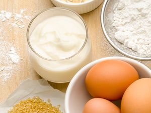 Bowl of eggs yogurt sugar flour and oatmeal on a wooden surface