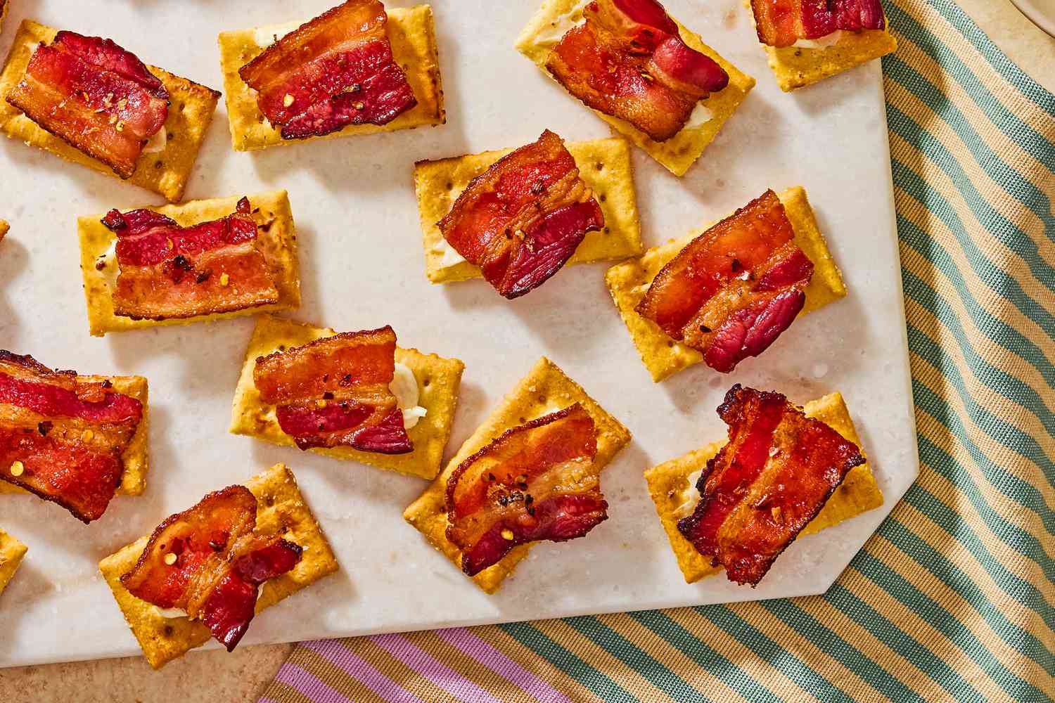 Closeup view of a serving board of millionaire crackers appetizer on top of a striped cloth napkin