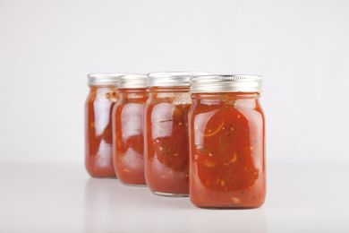Four glass jars filled with tomato sauce arranged in a row