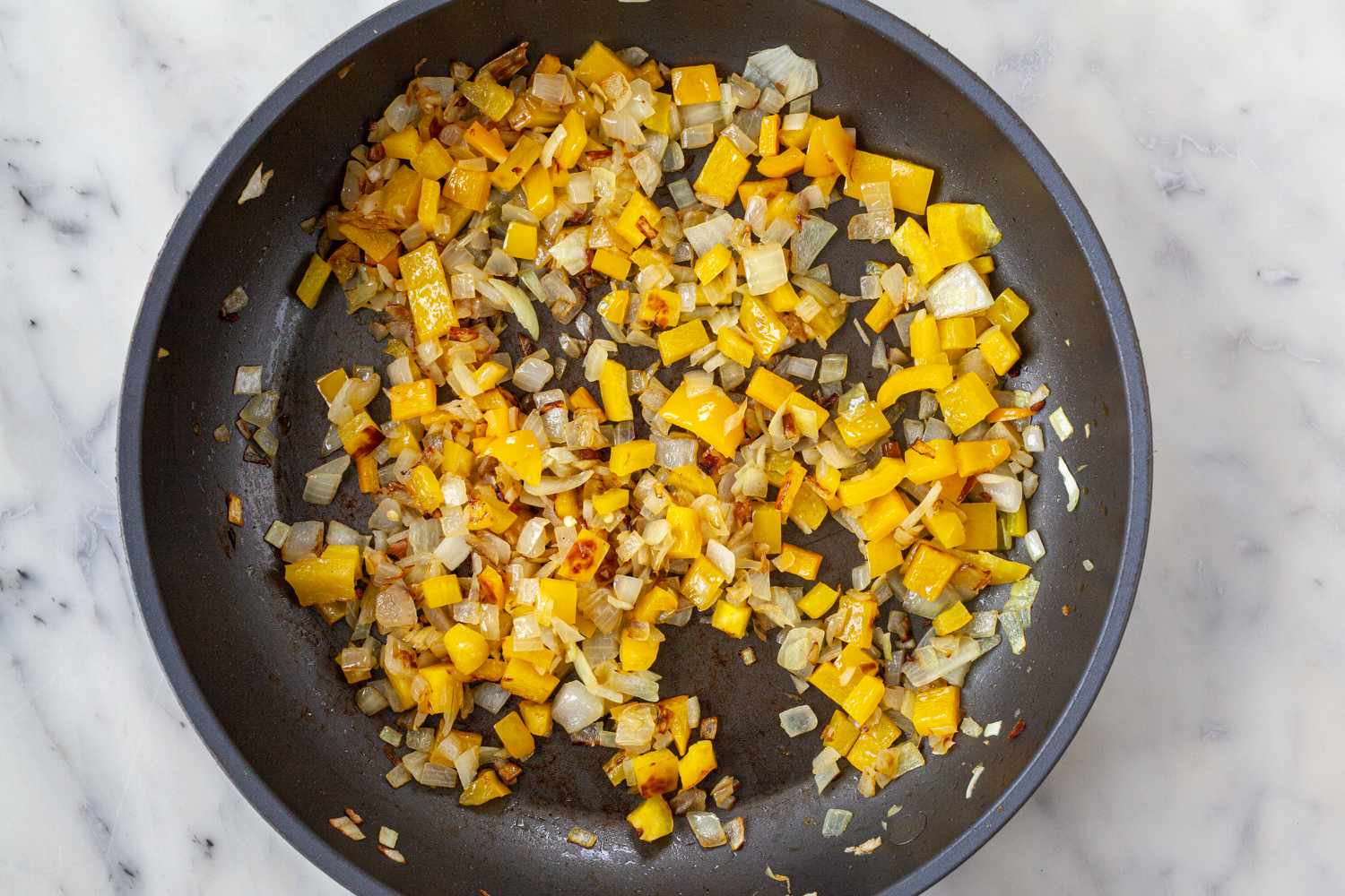 Cooking vegetables in a skillet for Spanish Style Migas with Asparagus, Chorizo, Bacon, and Eggs.