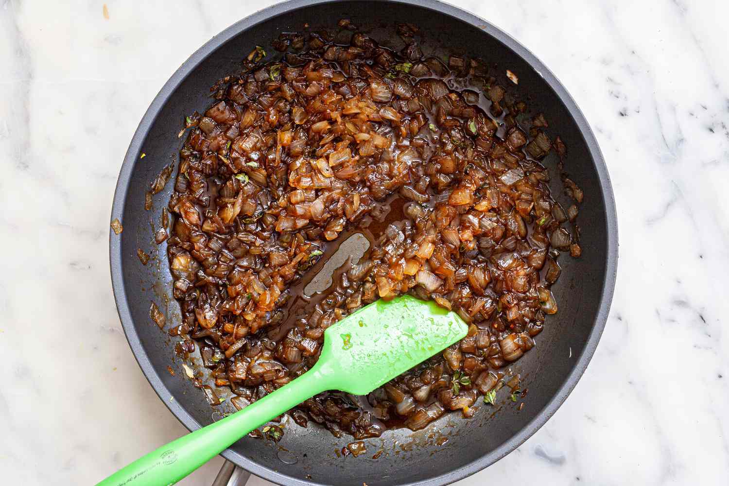 Stirring a skillet to make a balsamic onion jam.