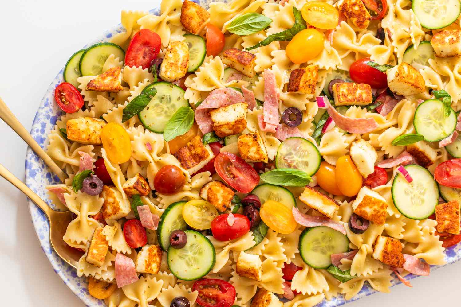 pasta salad in a bowl with serving utensils