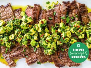 Grilled steak slices topped with avocado chimichurri and garnished with herbs