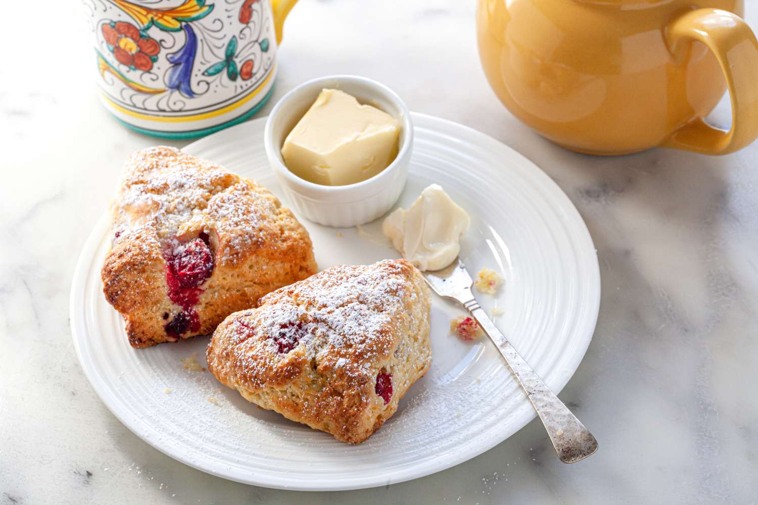 Citrus and cranberry scones on plate with butter.