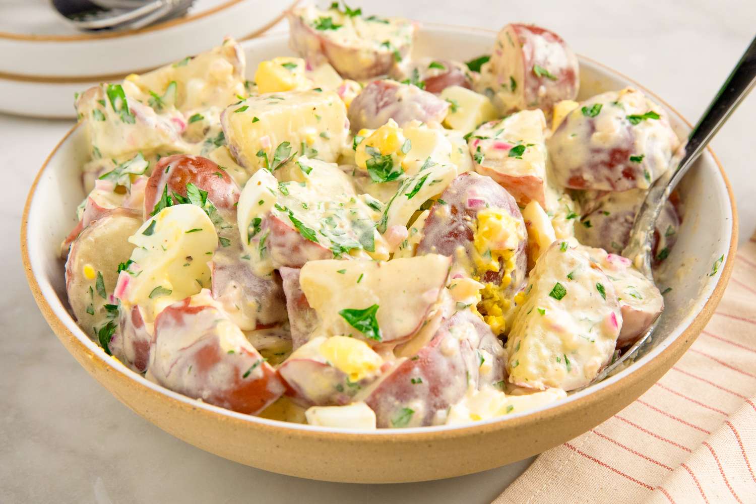 A bowl of potato salad with herbs and dressing