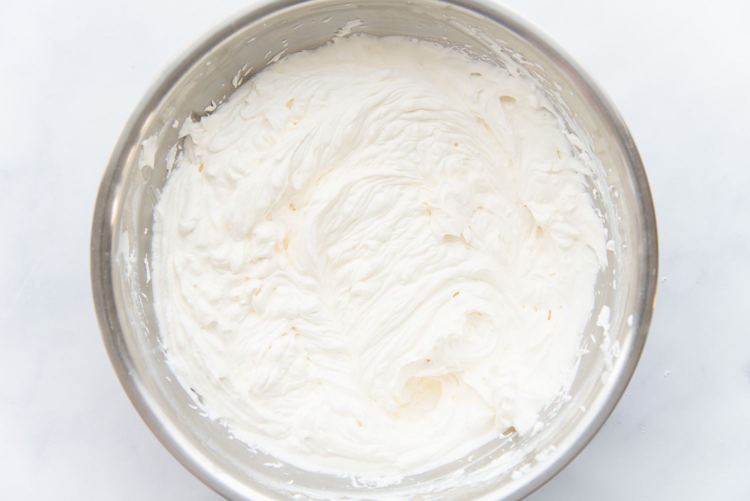 Overhead view of a bowl of stabilized whipped cream for a chocolate swiss roll.