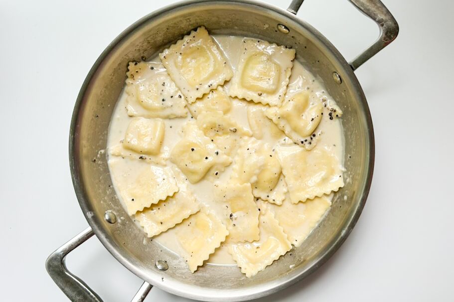 A pan of ravioli in a creamy sauce with black pepper prepared as a Cacio e Pepe style dish