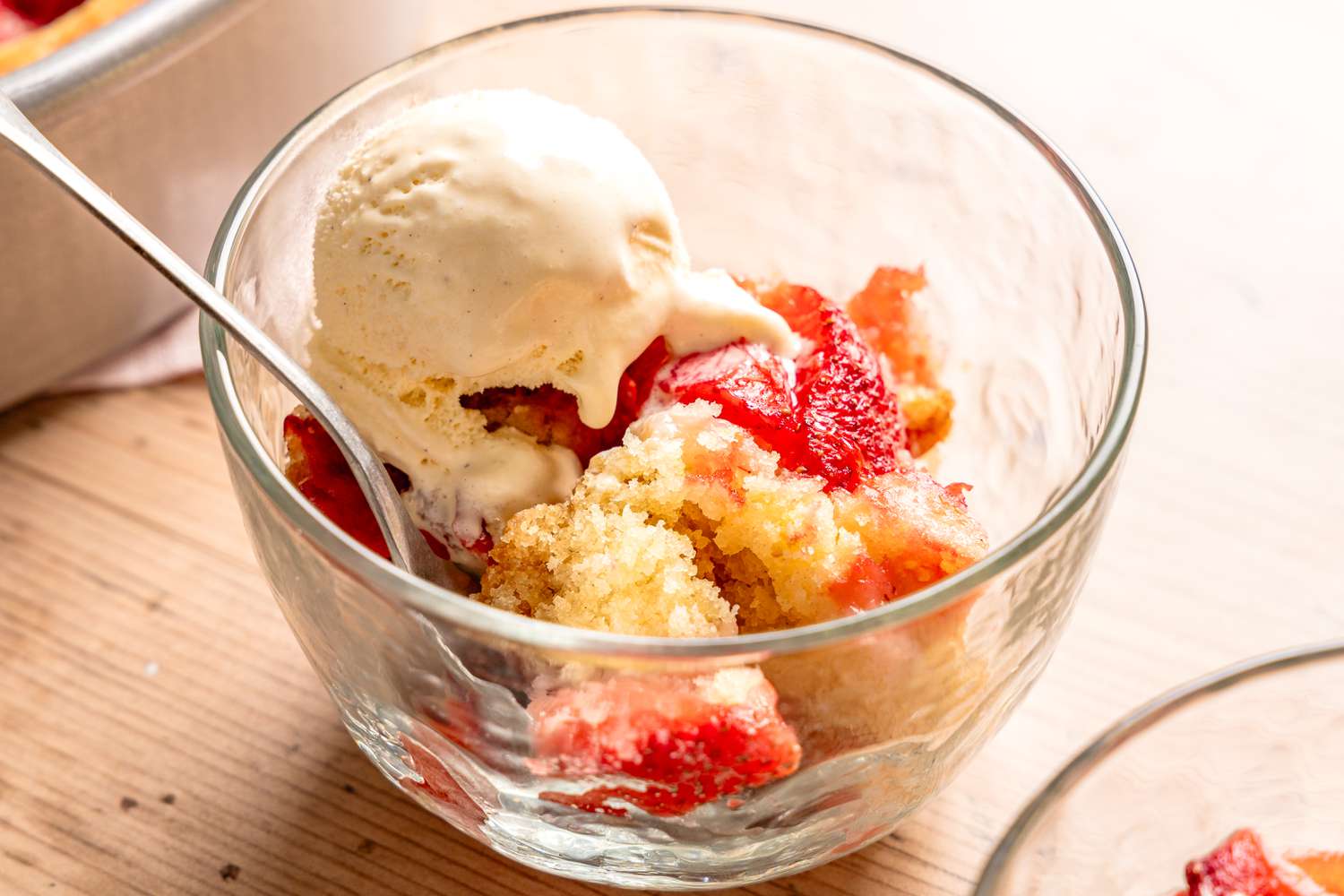 strawberry spoon cake in a bowl with a scoop of ice cream