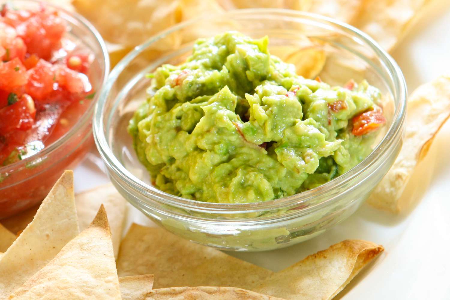 Guacamole and salsa in bowls with tortilla chips nearby