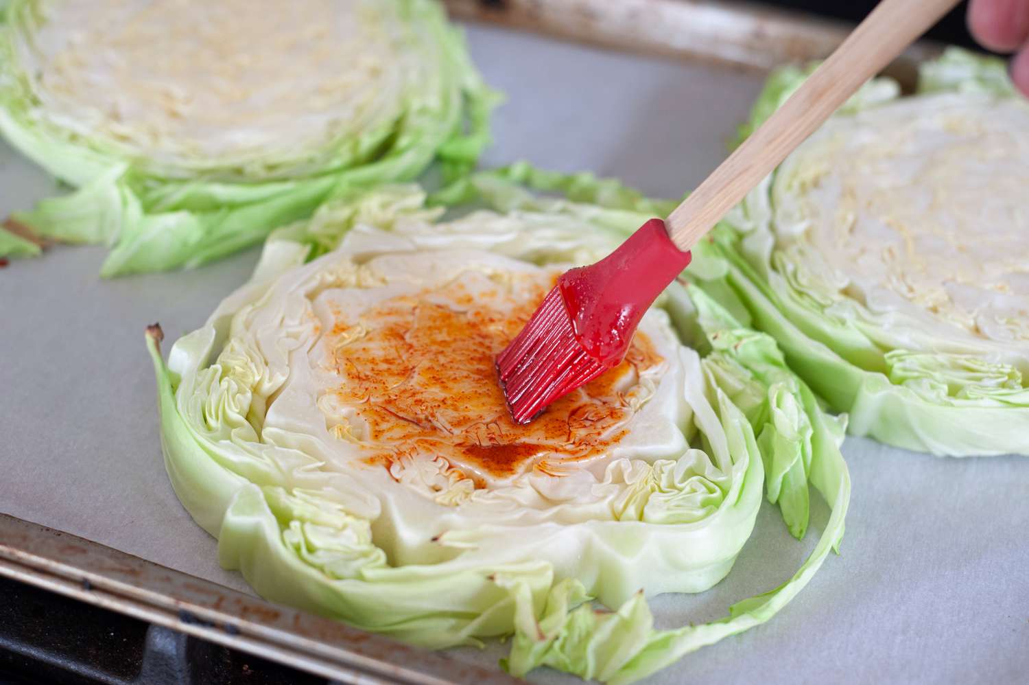 Brushing sauce on roasted cabbage steaks.
