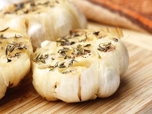 Roasted garlic seasoned with herbs on a wooden surface
