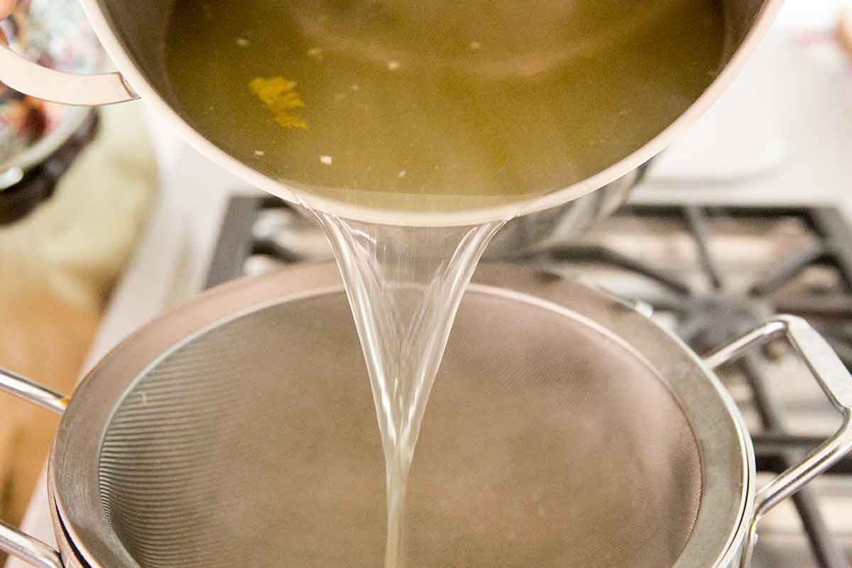 Turkey stock being poured through a strainer 
