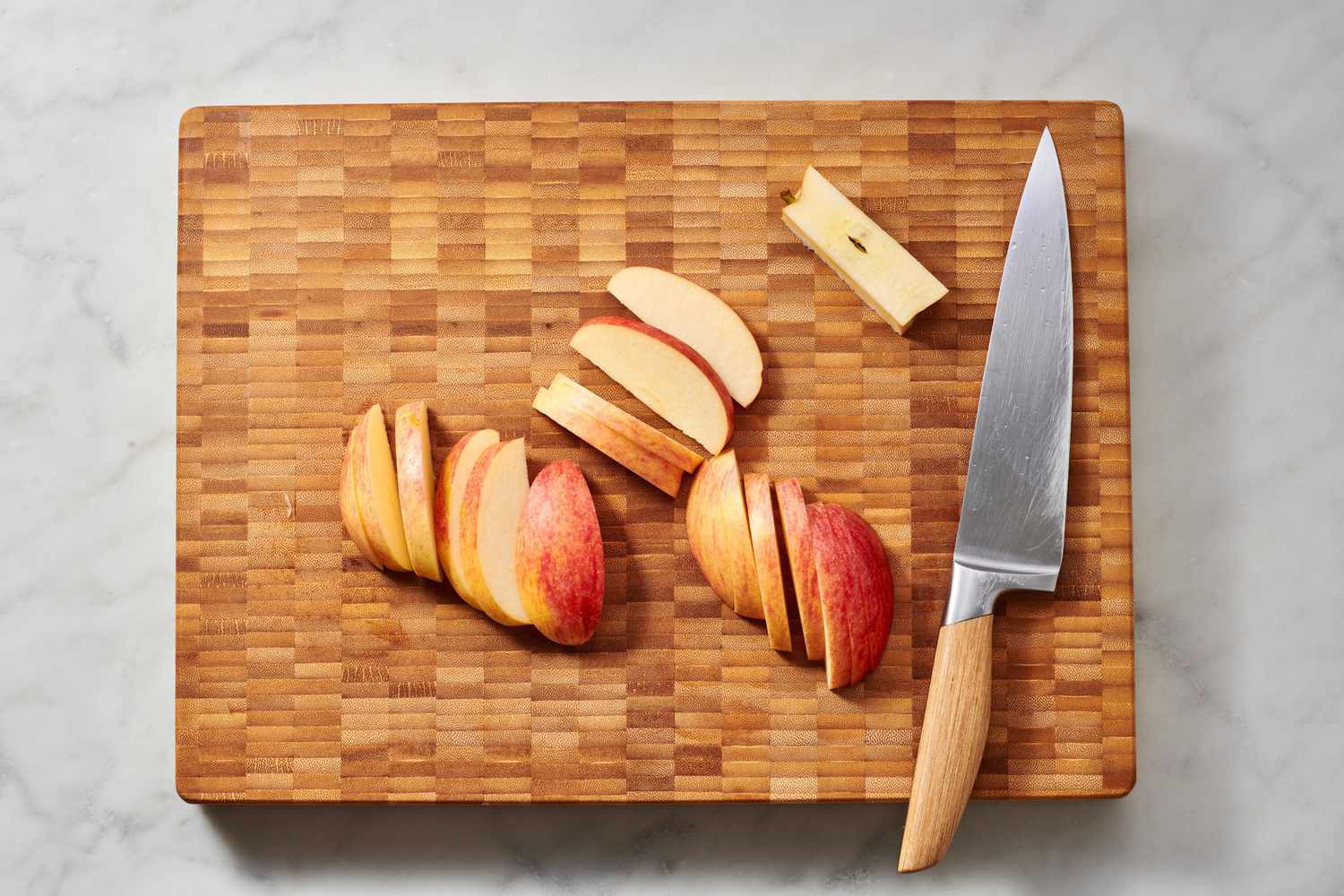Sliced apples on a wooden cutting board next to a knife