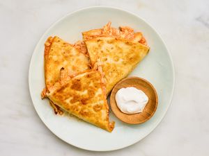 5-ingredient buffalo chicken quesadillas cut into slices and served on a plate with a bowl of sour cream