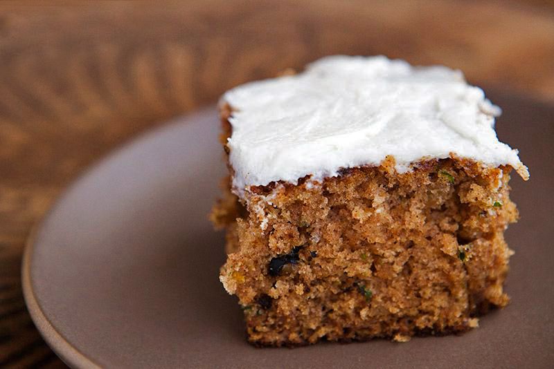 A plated square slice of zucchini cake with cream cheese frosting