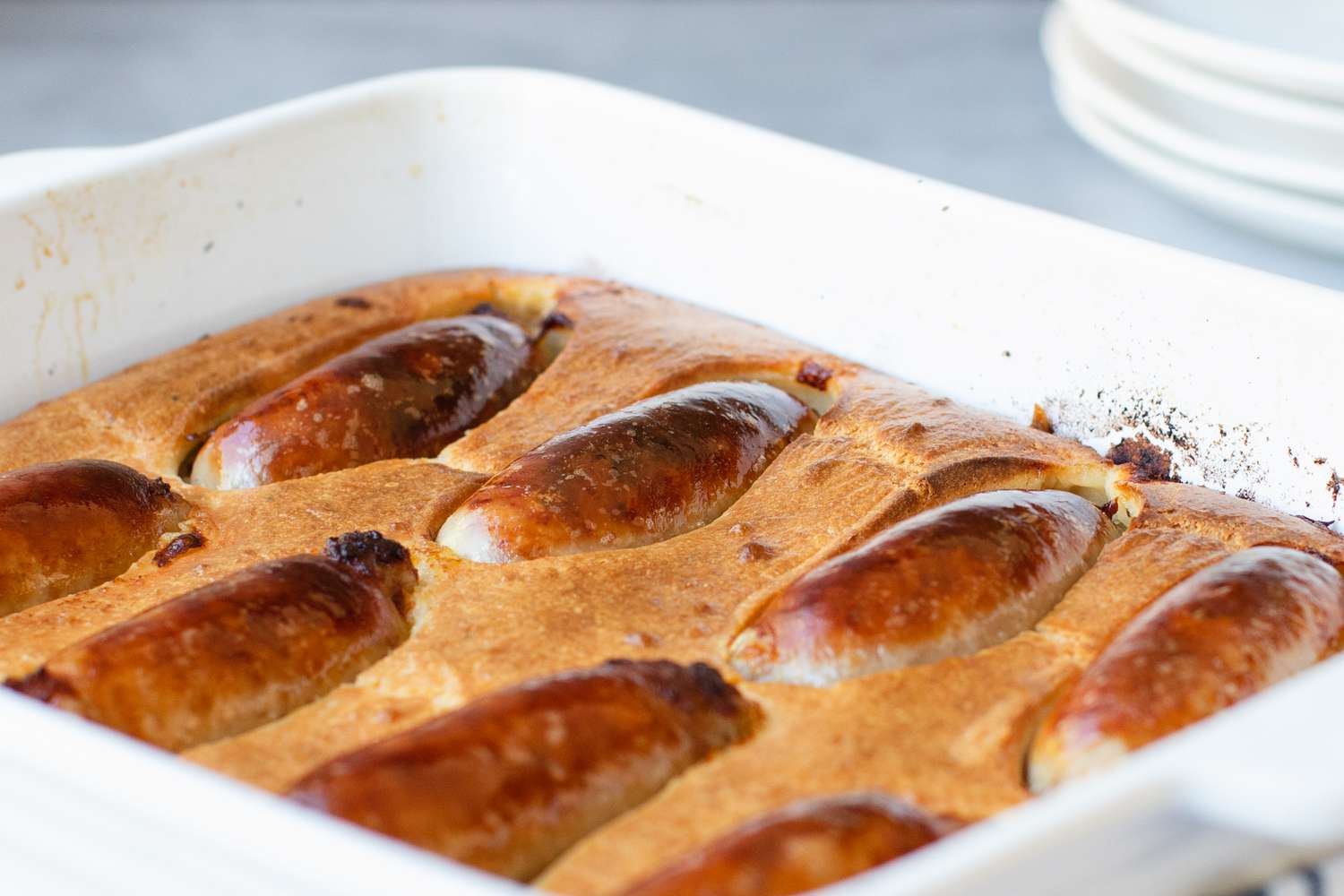 Toad in the hole in a white baking dish.