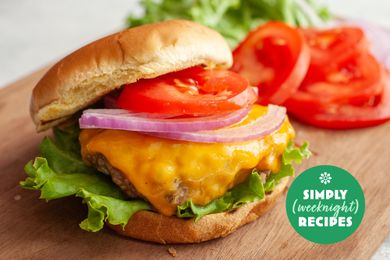 Cheeseburger with lettuce tomato and onion slices on a wooden board