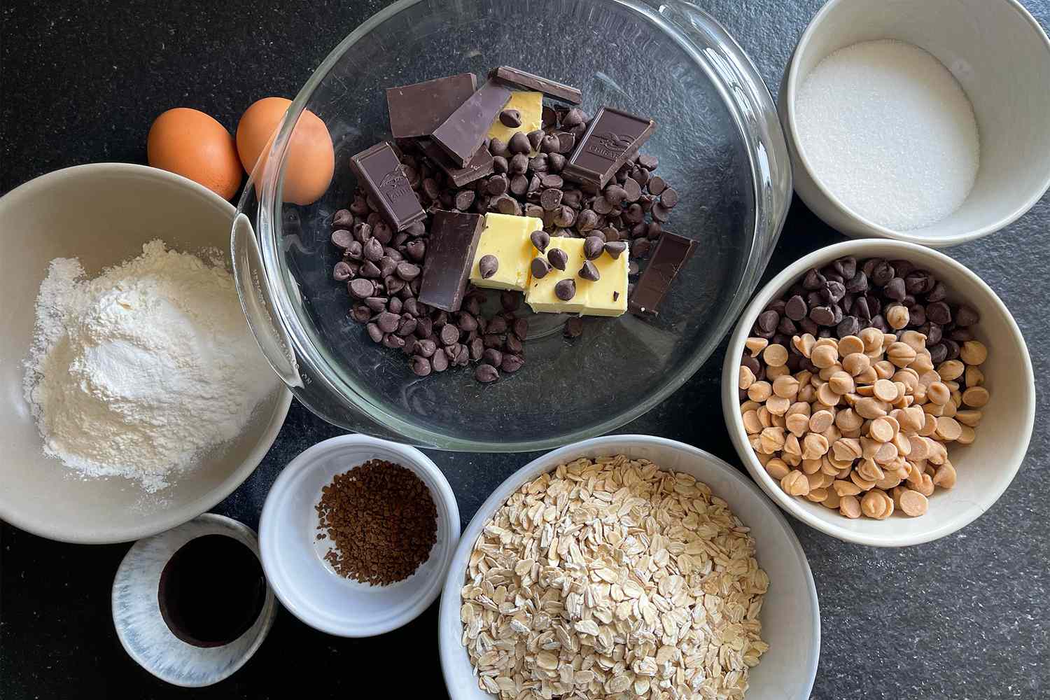 Ingredients for baking chocolate and peanut butter cookies including chocolate chips butter oats flour sugar and eggs