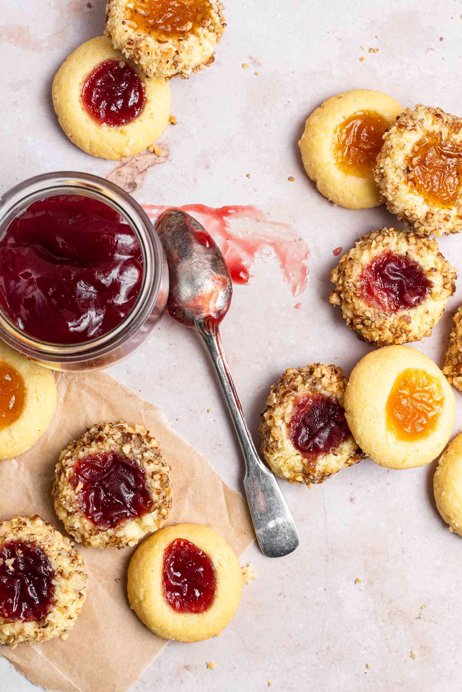 Classic thumbprint cookies and a jar of jam and a spoon in the middle of them.
