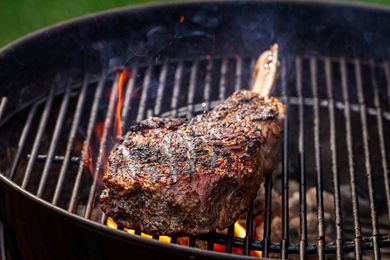 Seasoned bone in steak on a hot grill