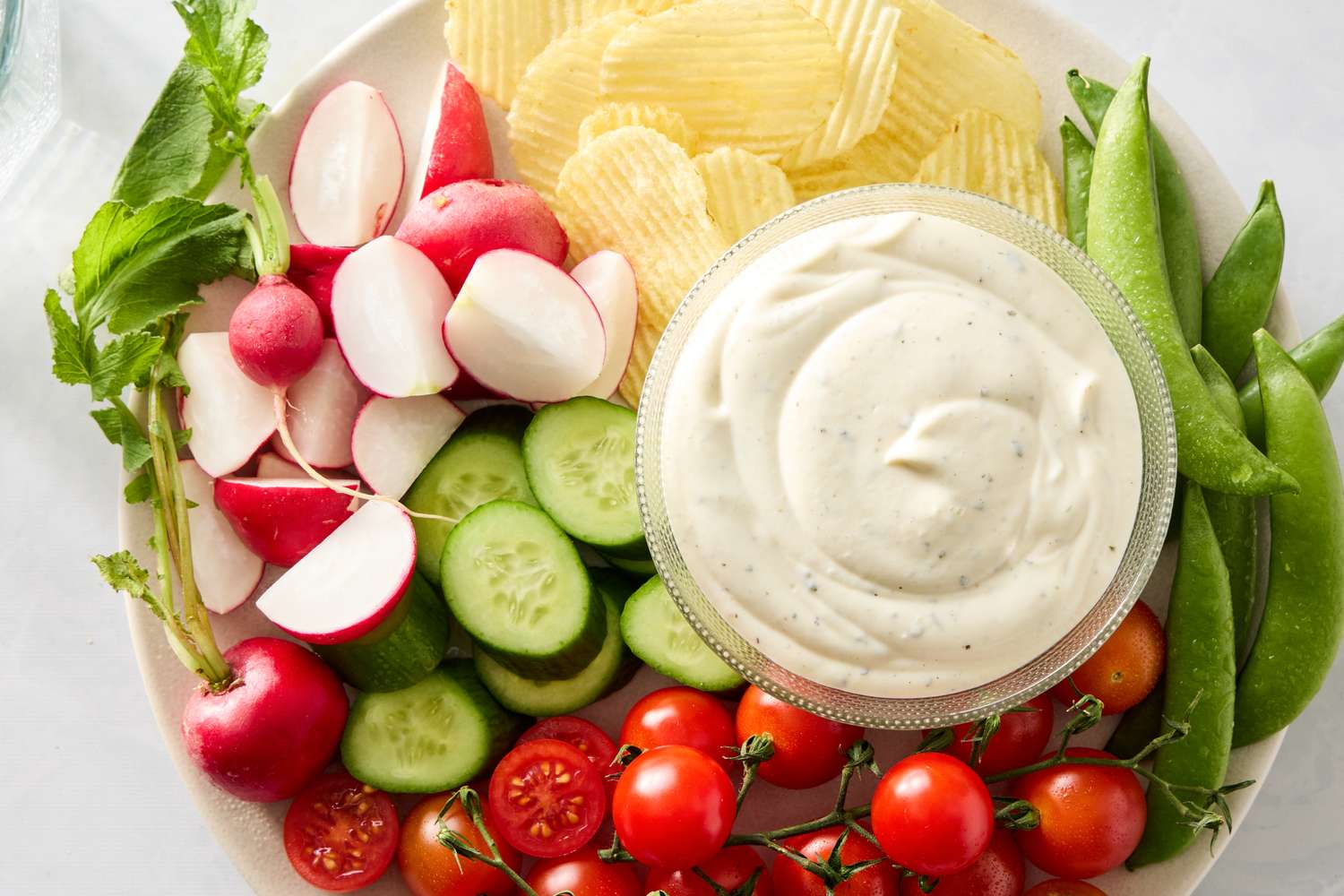 A plate of vegetables chips and a bowl of creamy dip