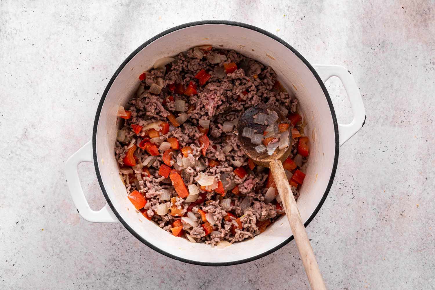 Ground Beef Mixed With the Diced Onions and Bell Peppers Using a Wooden Spatula for One-Pot Taco Pasta Recipe
