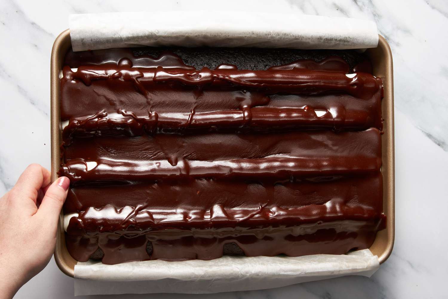 Pan moved from side to side to spread chocolate fudge topping for bumpy cake recipe