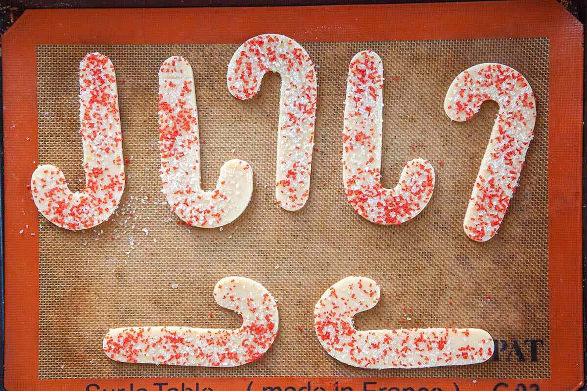 Candy cane shaped Homemade Sugar Cookies covered in sprinkles are ready to be baked.