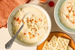 Bowls of creamy chicken mull soup with a spoon served with crackers