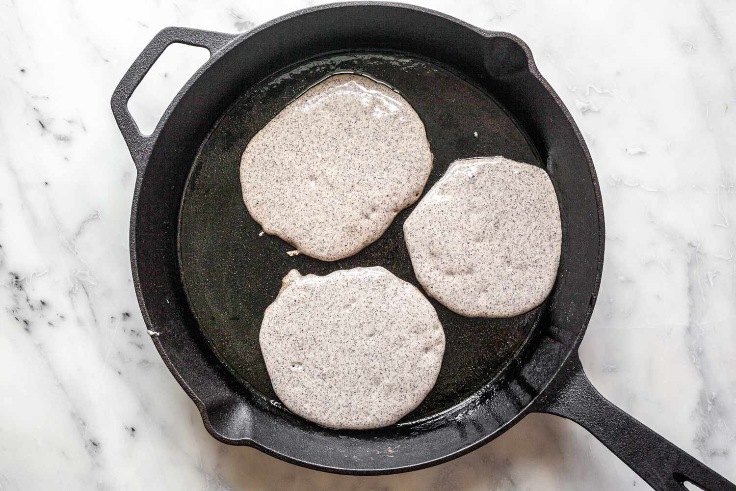 Buckwheat Pancakes Batter on a Hot Cast Iron Skillet 