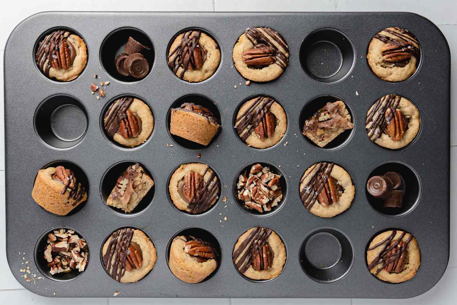 Turtle Cookie Cup in a Mini Muffin Tray with Some of the Cavities Filled with Chopped Pecans and Rolos 