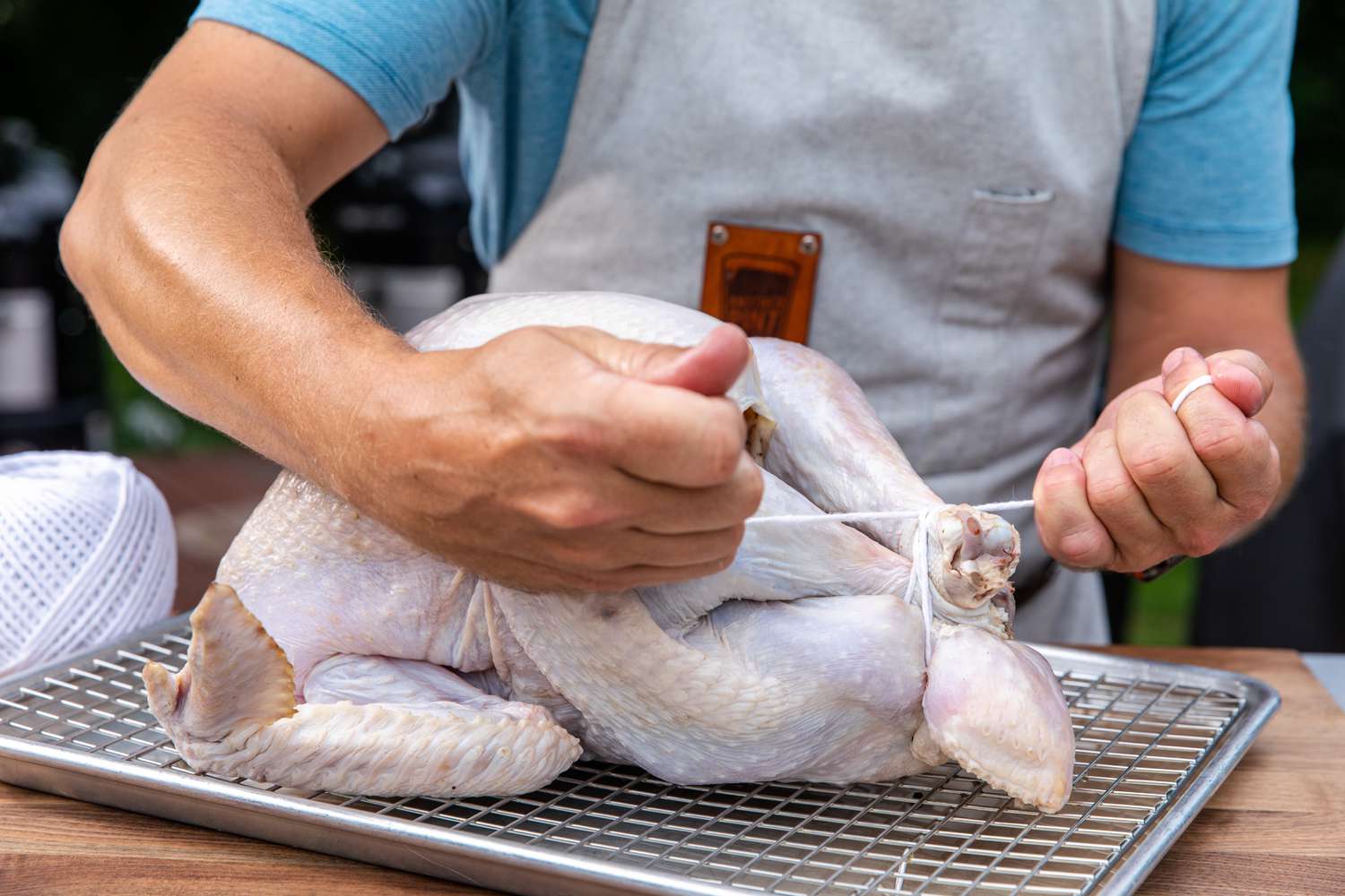 Tying the legs of a turkey to make a pecan wood smoked turkey.
