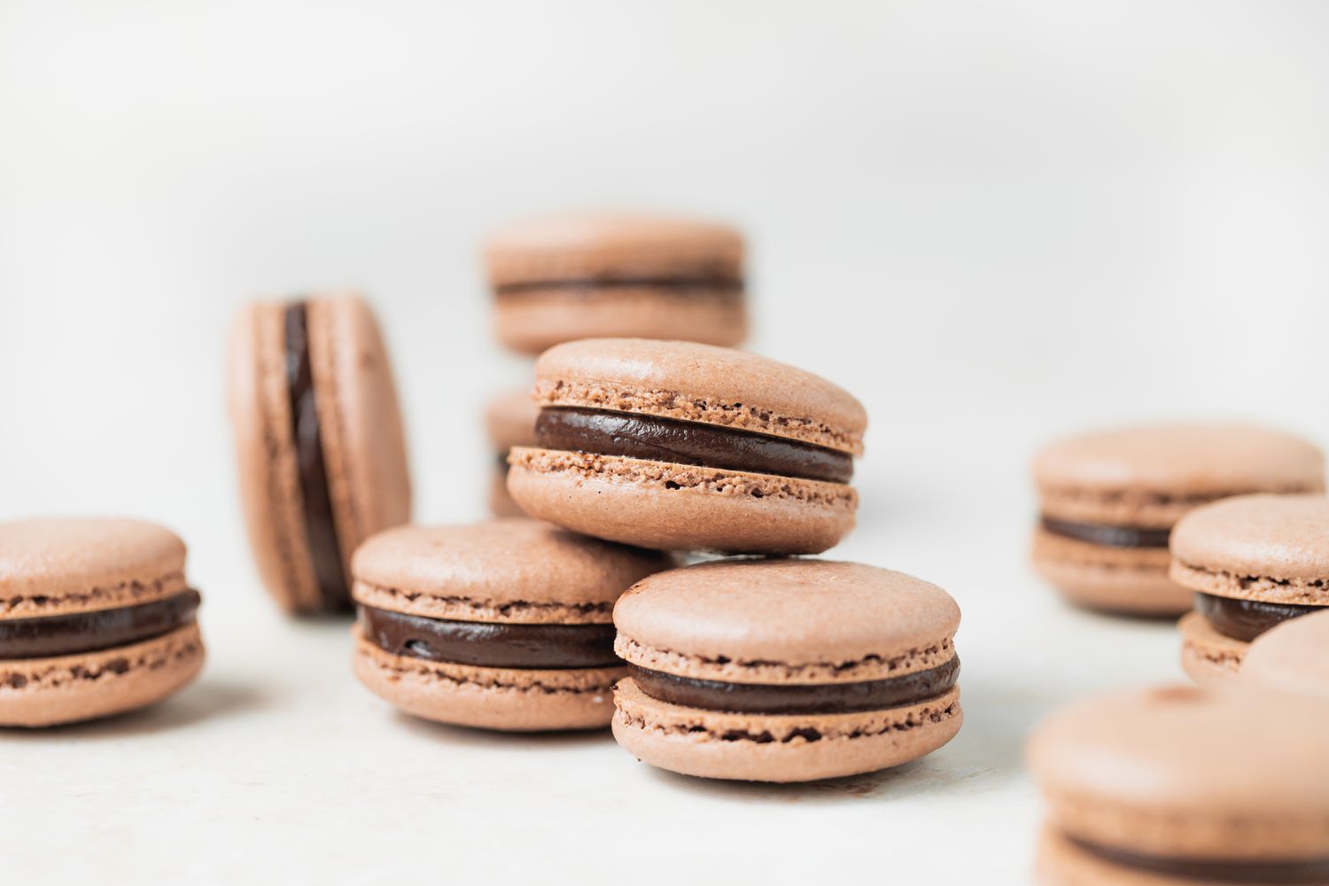 Side view of three chocolate macarons with dark chocolate ganache