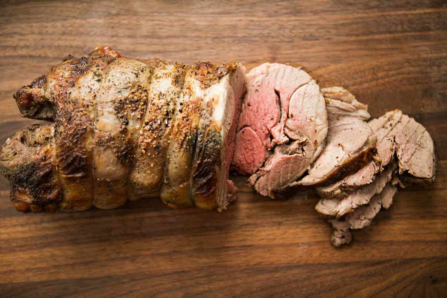 Roast leg of lamb on a wood cutting board.