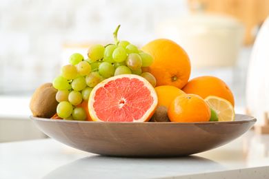 Bowl containing various fruits including a cut grapefruit grapes oranges and kiwis